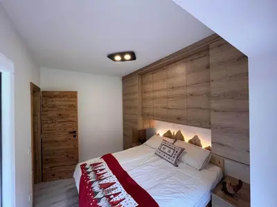 a bedroom with a large bed with a wooden wall at Sellaronda - Ciampac Experience in Alba di Canazei