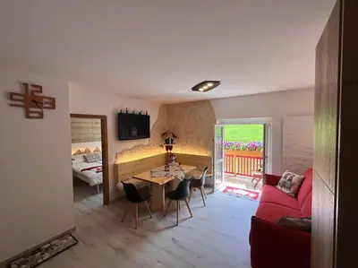 a living room with a red couch and a table at Sellaronda - Ciampac Experience in Alba di Canazei