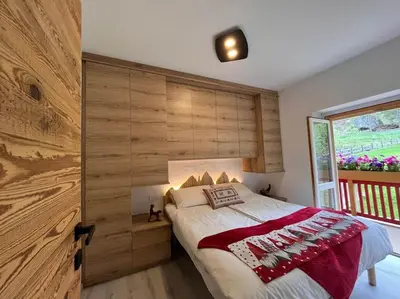 a bedroom with a bed with a wooden wall at Sellaronda - Ciampac Experience in Alba di Canazei