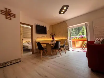 a living room with a table and chairs and a bedroom at Sellaronda - Ciampac Experience in Alba di Canazei