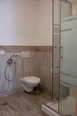 a bathroom with a toilet and a glass shower at City Apartments Portico in Merano