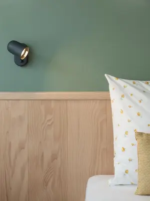 a lamp on a wall next to a bed with a pillow at Dianthus Apartment in Lana