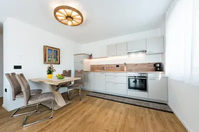 a kitchen with white cabinets and a wooden table at Lüch de Corona in Frena