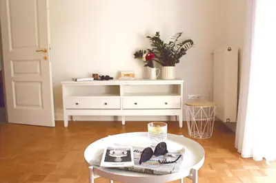 a living room with a table and a white dresser at Elina Apartment in Merano
