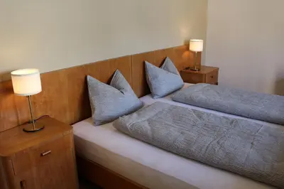 a bedroom with a bed with blue pillows and two lamps at Elina Apartment in Merano