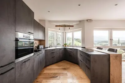 a kitchen with wooden floors and large windows at Dolomites Alpin Penthouse, 90qm, privat Sauna - privat Whirlpool in Mühlbach