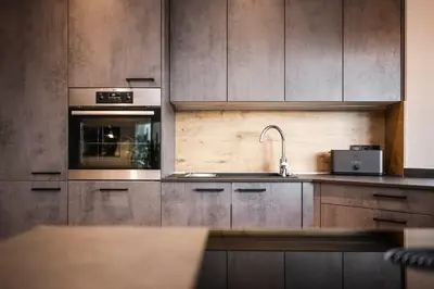 a kitchen with wooden cabinets and a sink and an oven at Dolomites Alpin Penthouse, 90qm, privat Sauna - privat Whirlpool in Mühlbach