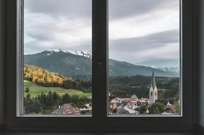 a window with a view of a town and mountains at Dolomites Alpin Penthouse, 90qm, privat Sauna - privat Whirlpool in Mühlbach