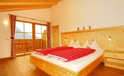 a bedroom with a bed with red pillows on it at Singerhof in Castelrotto