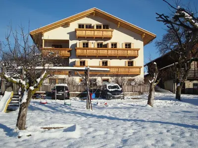 a house in the snow with cars parked in front at Singerhof in Castelrotto