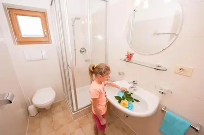 a little girl standing in a sink in a bathroom at Singerhof in Castelrotto