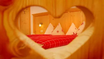 a bedroom with a red bed with white pillows at Singerhof in Castelrotto