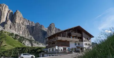 a building on the side of a mountain at Alpin Hotel & Restaurant Frara in Selva di Val Gardena