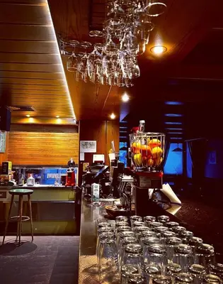 a bar with a bunch of glasses on a counter at Alpin Hotel & Restaurant Frara in Selva di Val Gardena