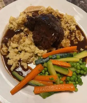 a plate of food with meat and rice and vegetables at Alpin Hotel & Restaurant Frara in Selva di Val Gardena