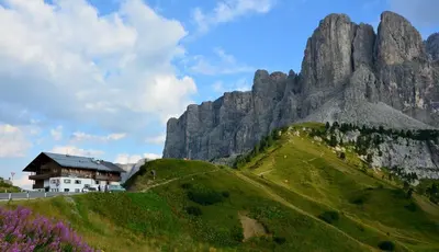 a house on a hill next to a mountain at Alpin Hotel & Restaurant Frara in Selva di Val Gardena