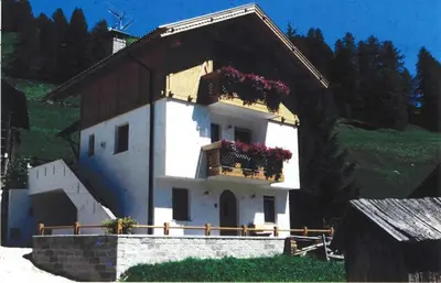 a small white house with flower boxes on it at Appartamenti Loega in San Cassiano