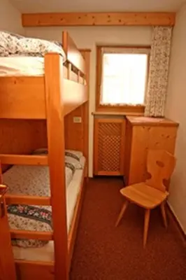a bed in a bedroom with a wooden bed frame at Appartamenti Loega in San Cassiano