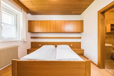 a bedroom with a bed and wooden cabinets at Apartments Chalet Zirm in Santa Cristina in Val Gardena