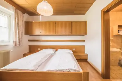 a bed in a room with wooden cabinets at Apartments Chalet Zirm in Santa Cristina in Val Gardena