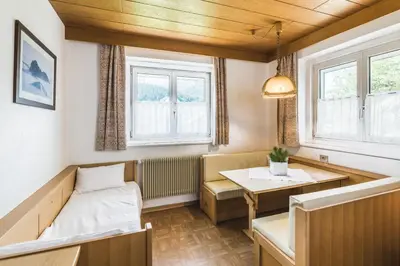 a room with a bed and a table and windows at Apartments Chalet Zirm in Santa Cristina in Val Gardena