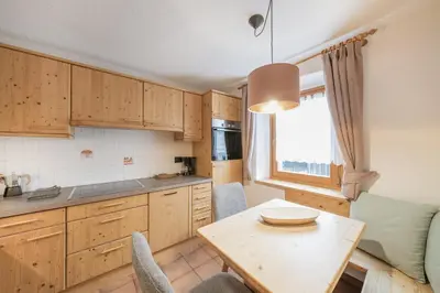 a kitchen with wooden cabinets and a table with chairs at Apartments Carmen in Ortisei
