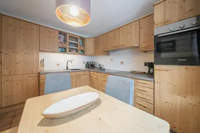 a kitchen with wooden cabinets and a wooden table at Apartments Carmen in Ortisei