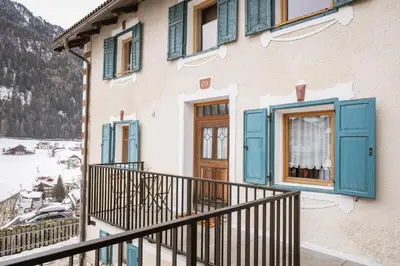a house with blue windows and a balcony at Apartments Carmen in Ortisei
