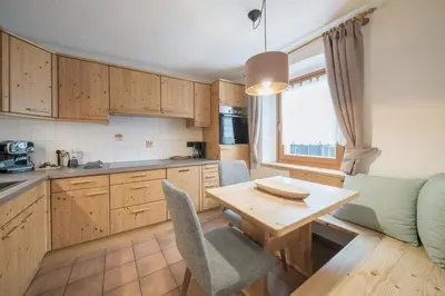 a kitchen with wooden cabinets and a table and chairs at Apartments Carmen in Ortisei