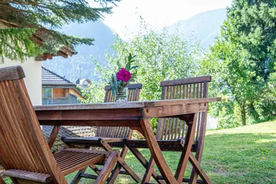 a wooden table with two chairs and a flower on it at Apartments Elmarino in Ortisei