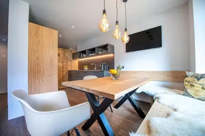 a dining room with a wooden table and white chairs at Apartments Elmarino in Ortisei