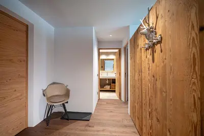 a hallway with a chair and a wooden wall at Apartments Elmarino in Ortisei