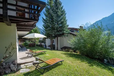 a patio with two benches and an umbrella at Apartments Elmarino in Ortisei
