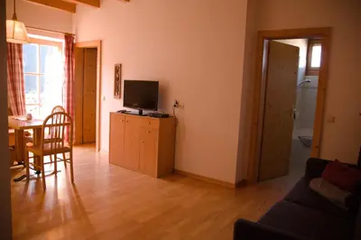 a living room with a television and a table with a chair at Messner Hof in Tires