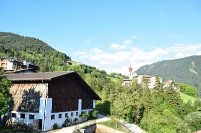 a building on a hill with a hot air balloon in the background at Messner Hof in Tires