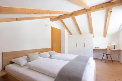 a large white bed in a room with wooden ceilings at Charmantes Ferienhaus in Eppan, Südtirol, ganzes Haus nahe Montiggler Badeseen und Bozen in Appiano sulla Strada del Vino