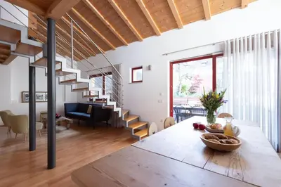 a living room with a wooden table and a spiral staircase at Charmantes Ferienhaus in Eppan, Südtirol, ganzes Haus nahe Montiggler Badeseen und Bozen in Appiano sulla Strada del Vino