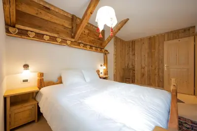a bedroom with a large white bed and wooden walls at Cesa Anna in Campitello di Fassa