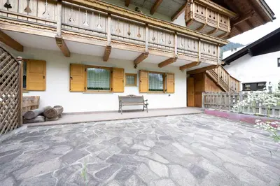 a patio with a bench in front of a building at Cesa Anna in Campitello di Fassa