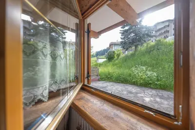 a window in a house with a view of a yard at Cesa Anna in Campitello di Fassa
