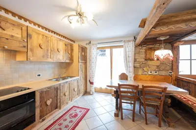 a kitchen with wooden cabinets and a table and chairs at Cesa Anna in Campitello di Fassa