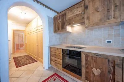 a kitchen with wooden cabinets and a stove top oven at Cesa Anna in Campitello di Fassa
