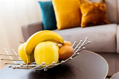 a bowl of fruit on a table with bananas and oranges at Ramoser Living Apartments in San Martino
