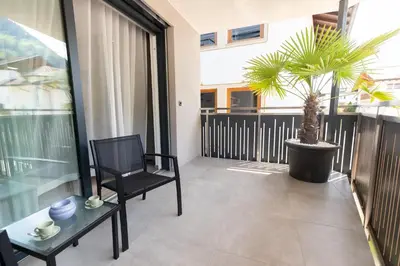 a balcony with a black chair and a potted plant at Ramoser Living Apartments in San Martino