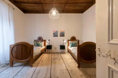 two beds in a room with wooden floors at der Paterhof- wohnen in historischen Mauern in Pianizza di Sopra