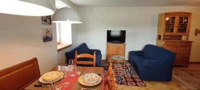 a living room with a table and chairs and a television at Ai Grisi in Cavalese