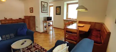 a living room with a blue couch and a table at Ai Grisi in Cavalese