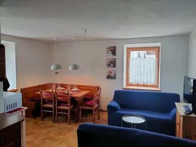 a dining room with a table and a blue couch at Ai Grisi in Cavalese