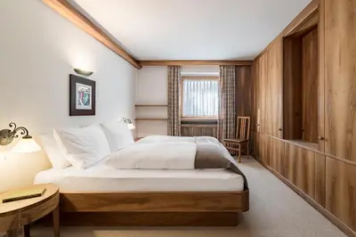 a bedroom with a bed and a table and a chair at Cësa Marmolada 1318 in Ortisei