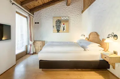 a bedroom with a large white bed and a television at Cësa Marmolada 1318 in Ortisei